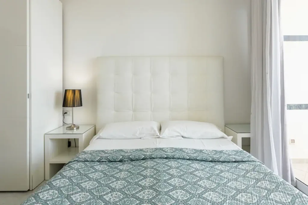Bright bedroom with white upholstered bed and window