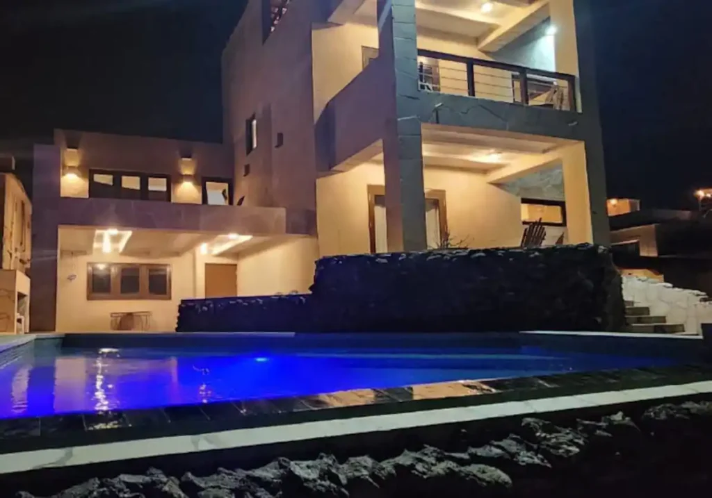 The Loft illuminated at night above a private pool