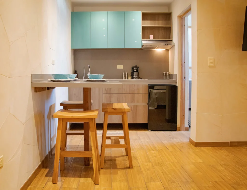 Compact kitchenette with turquoise cabinetry inside The Loft