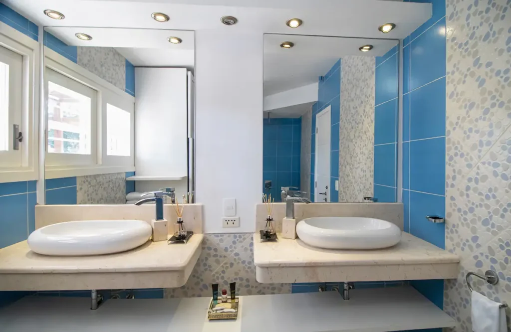 Blue tiled bathroom with twin basins at Villa Aurora