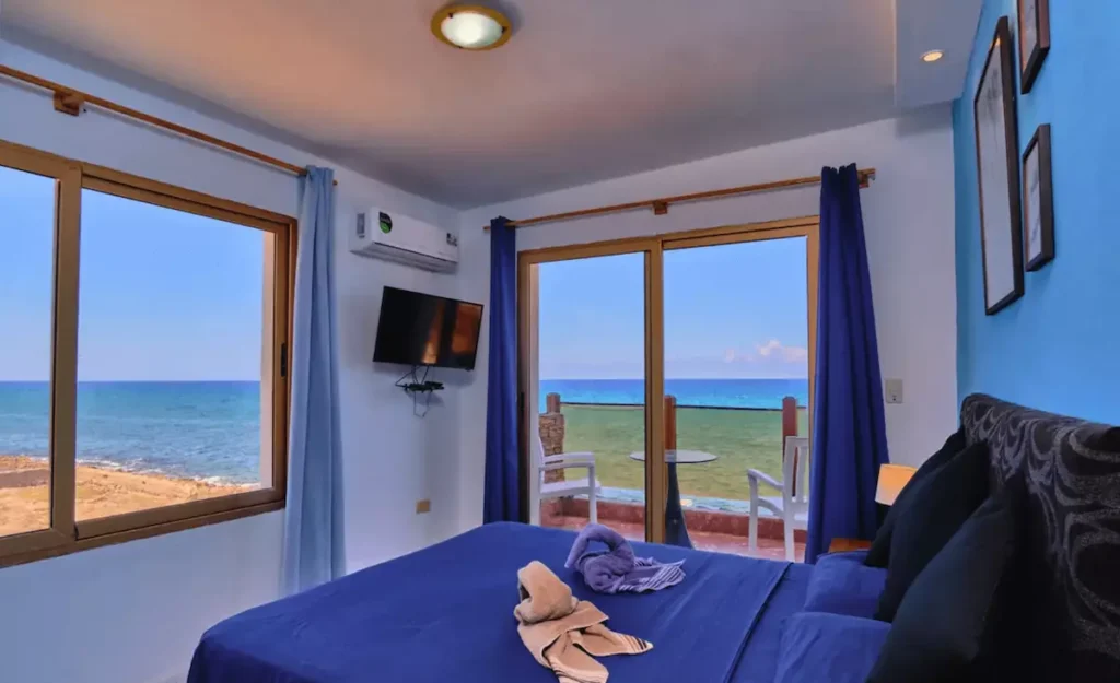 Blue bedroom with a large sea-view window at Villa Isis