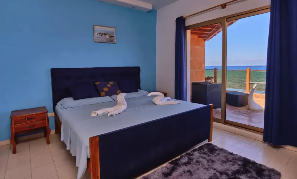 Blue bedroom opening onto a sea-facing balcony at Villa Isis