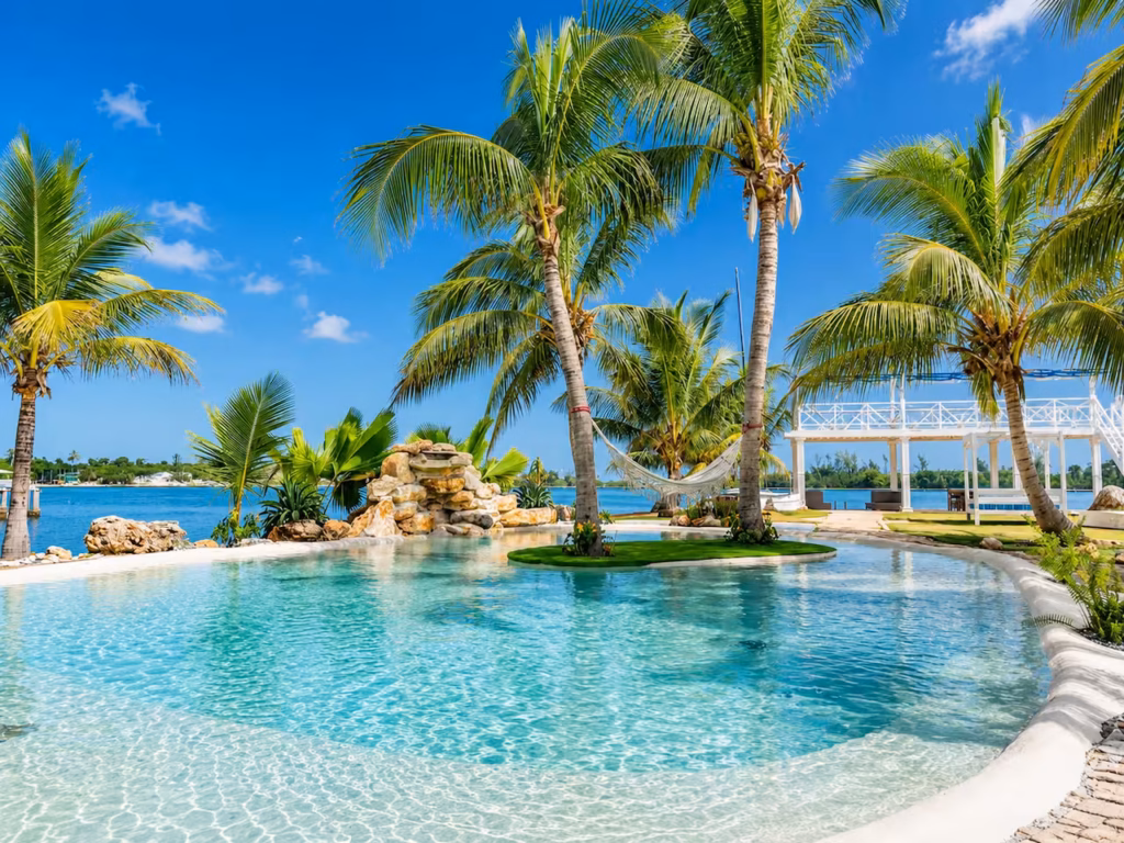 Palm-lined pool beside the water at Villa Palm Cay