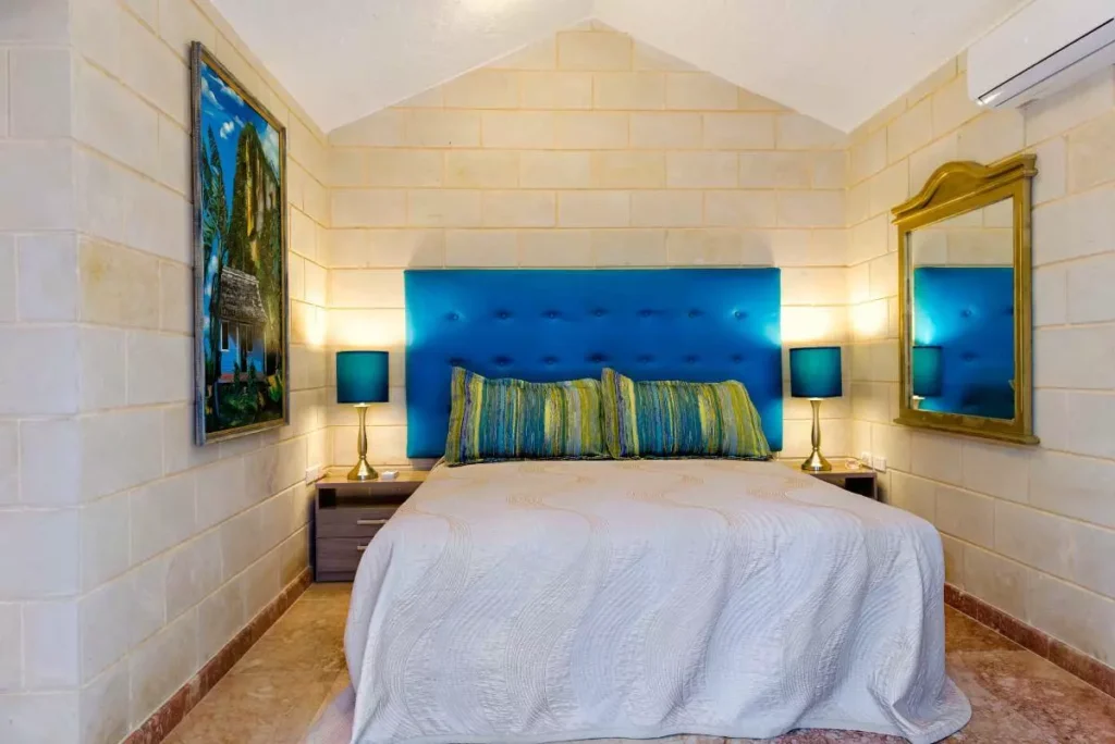 Stone-wall queen bedroom with blue headboard at Villa Yan